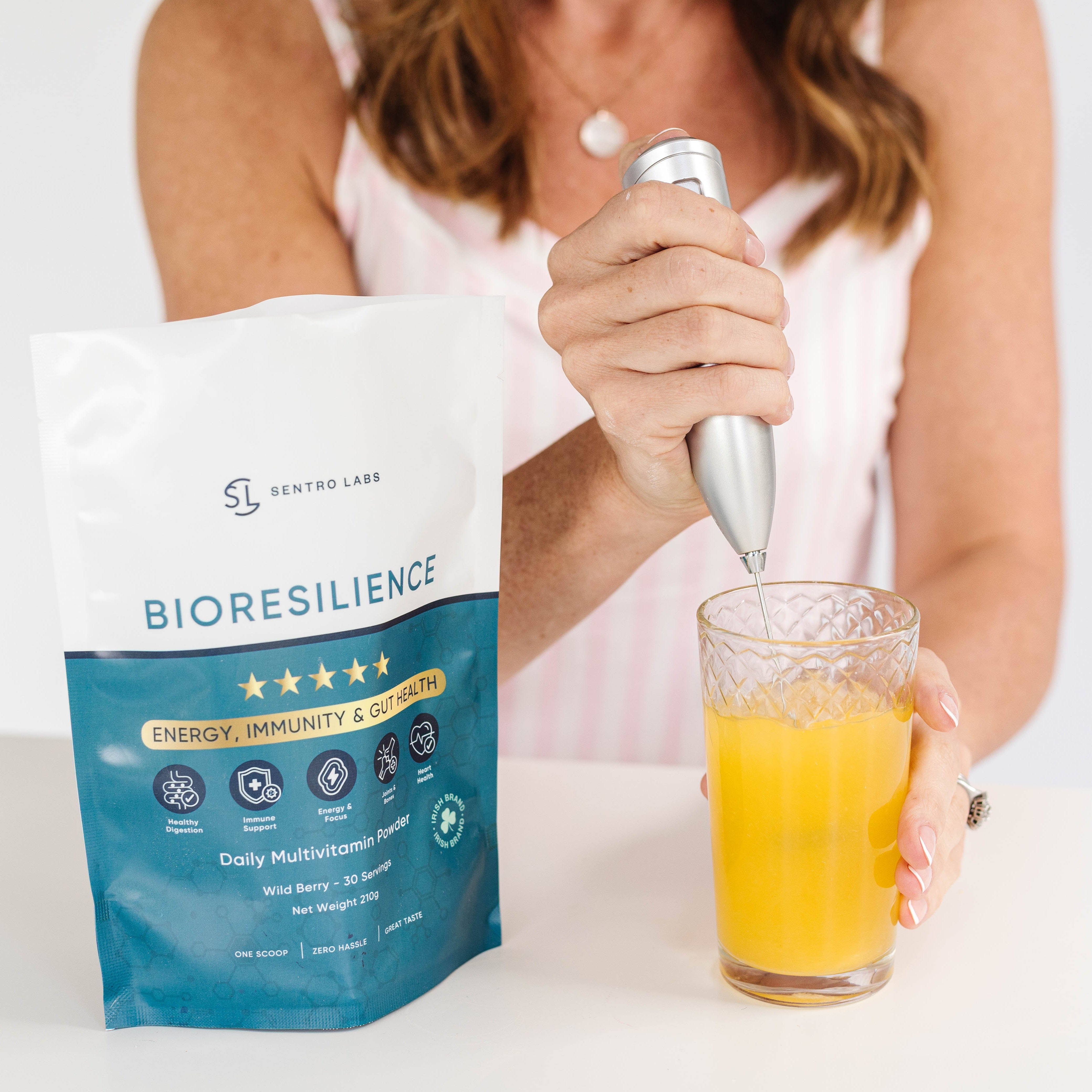 Person mixing a supplement into a glass of water with Bioresilience packaging.
