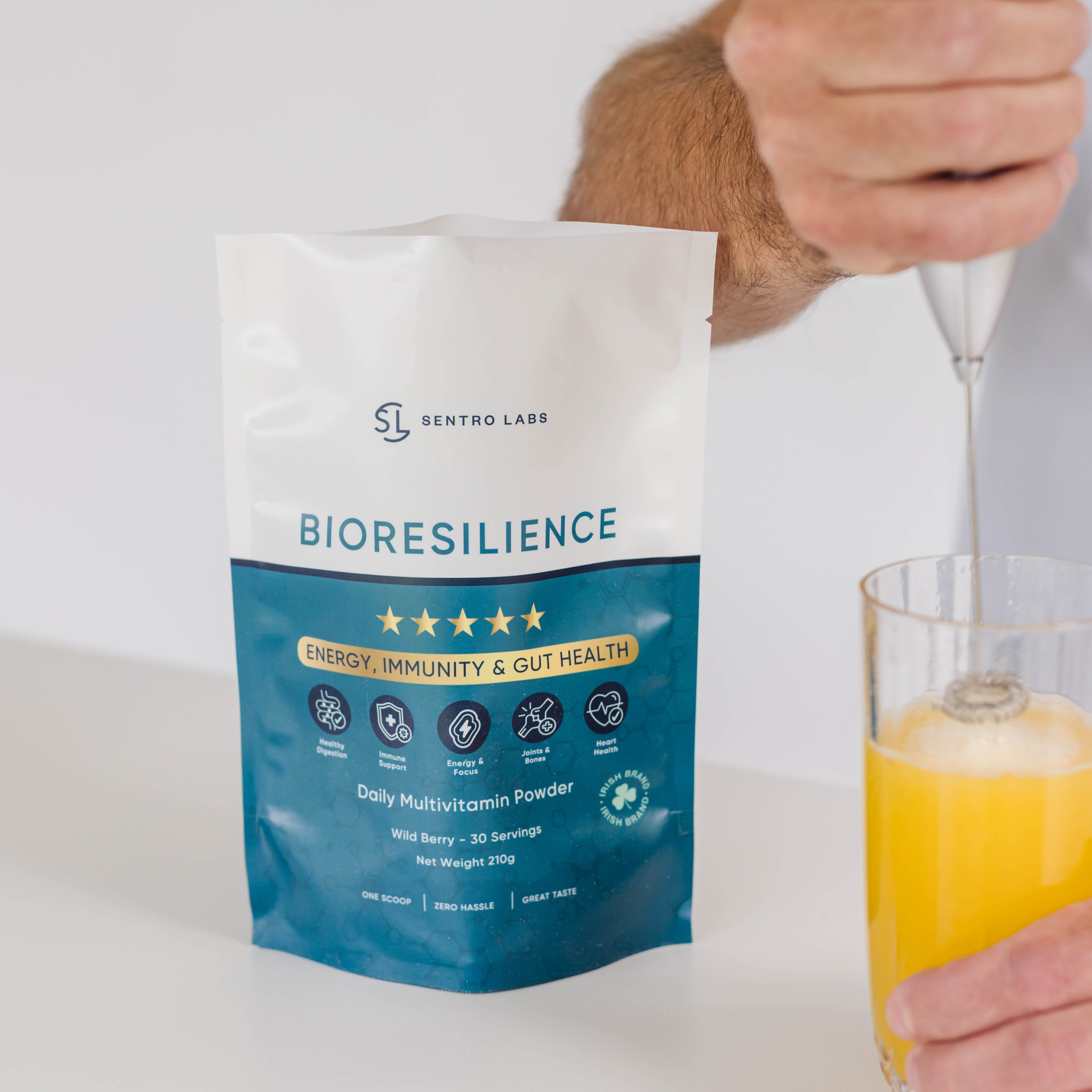 Person holding a Bioresilience supplement package with a glass of water and bioresilience powder getting mixed together
